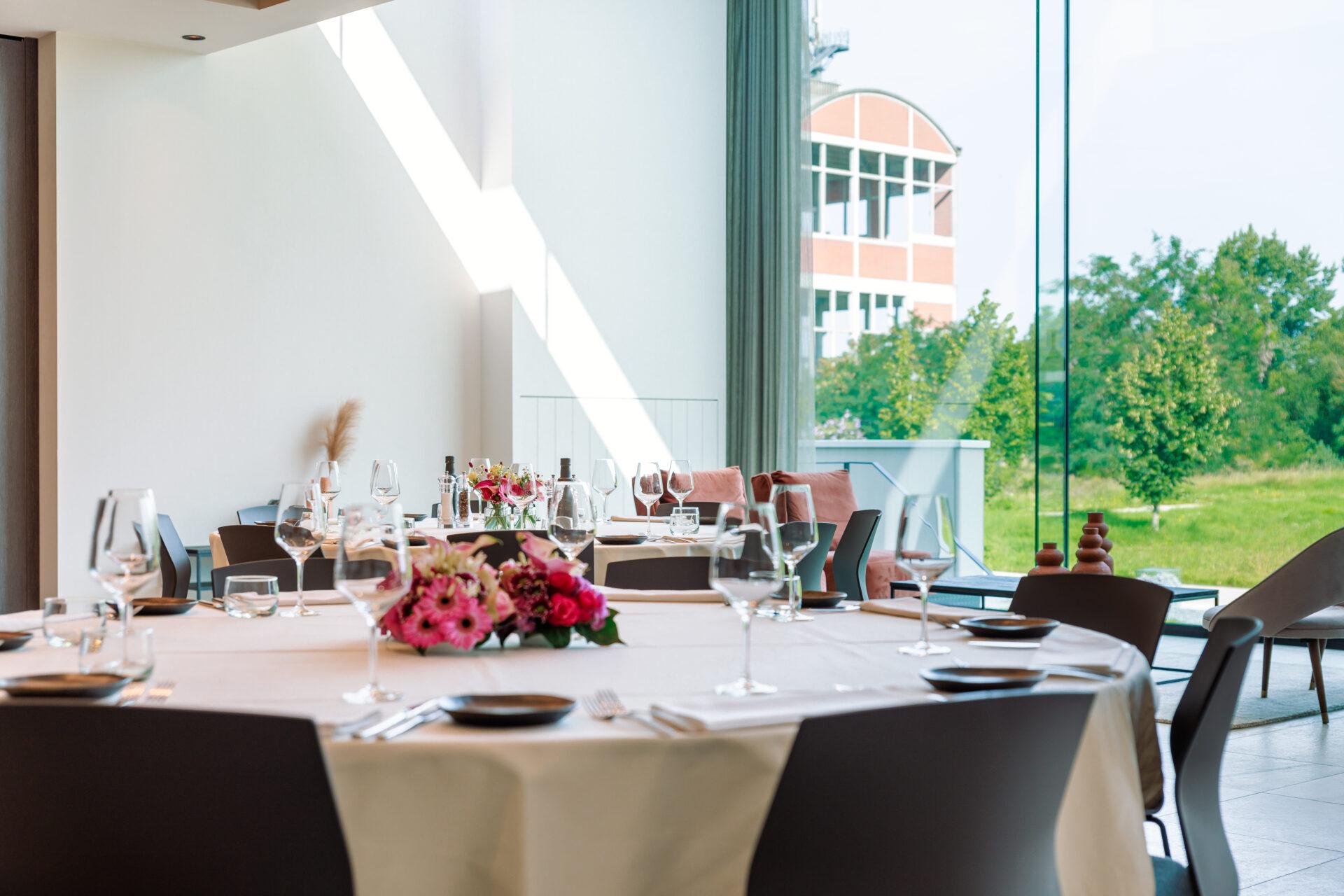 Stijlvol gedekte ronde tafels met grote ramen in de Terhillszaal