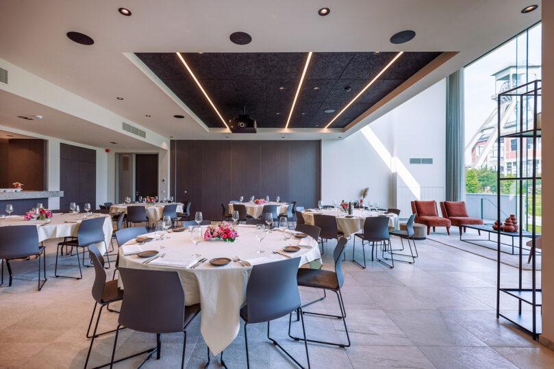 Stijlvolle feestopstelling met gedekte ronde tafels en grote ramen in de Terhillszaal